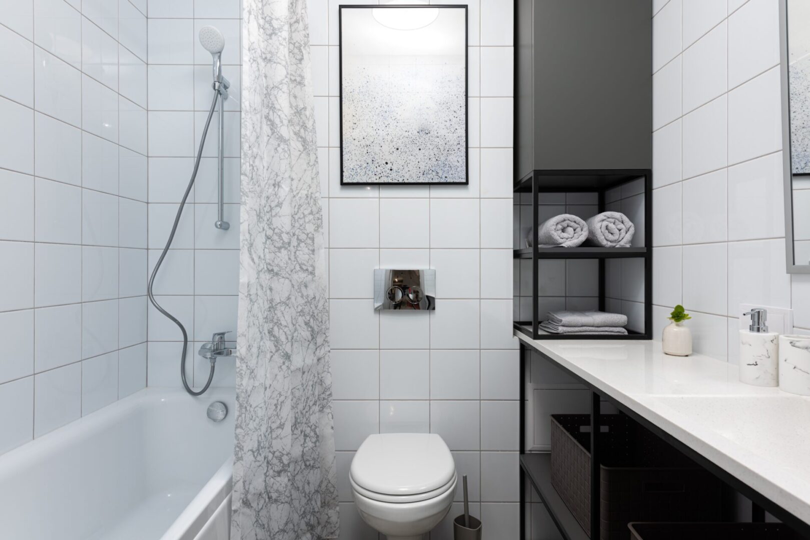 A bathroom with white tile and black accents.